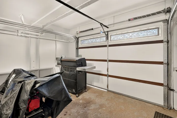 Garage interior featuring a white overhead door with decorative glass inserts and wood-finish accents