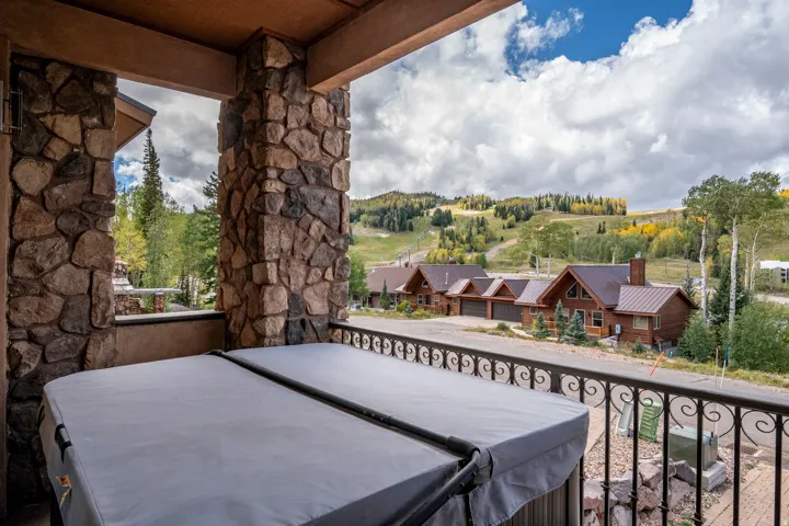Covered outdoor patio featuring stone columns and a hot tub