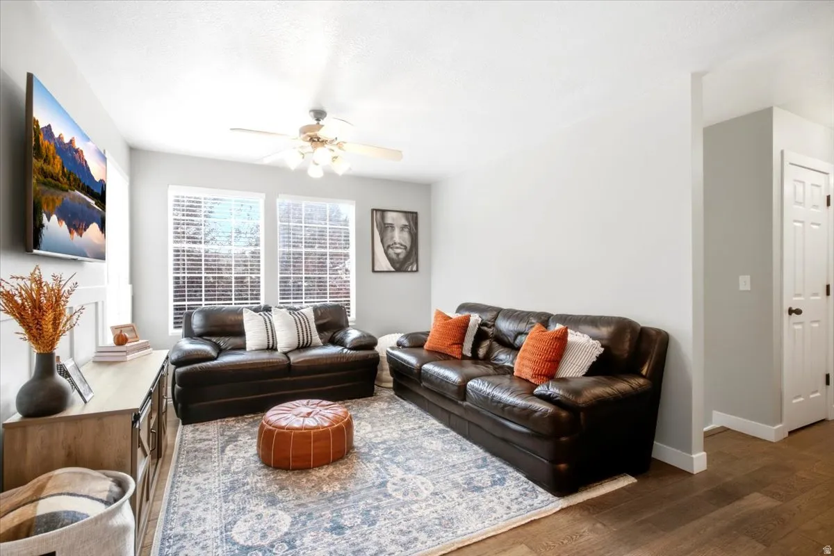 Recessed lighting and ceiling fan fixture illuminate the living area with wood-finish flooring