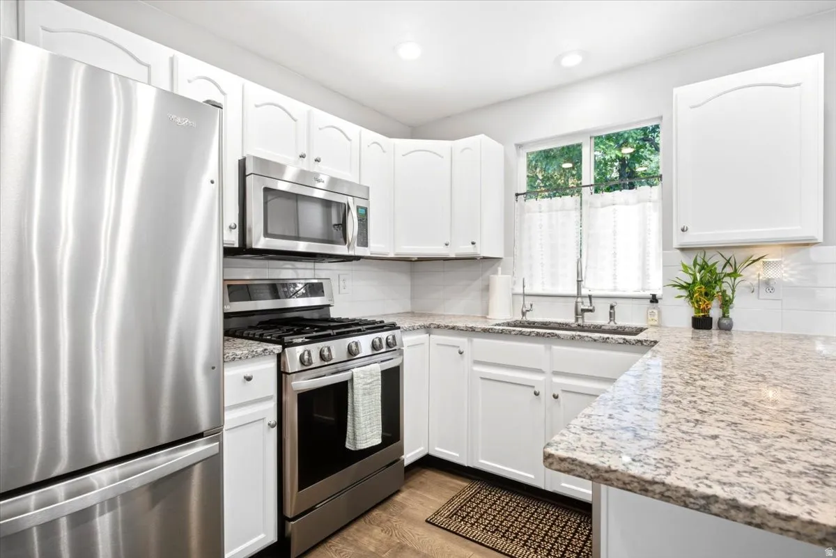 White cabinetry, stainless steel appliances, granite countertops, subway tile backsplash, and recessed lighting