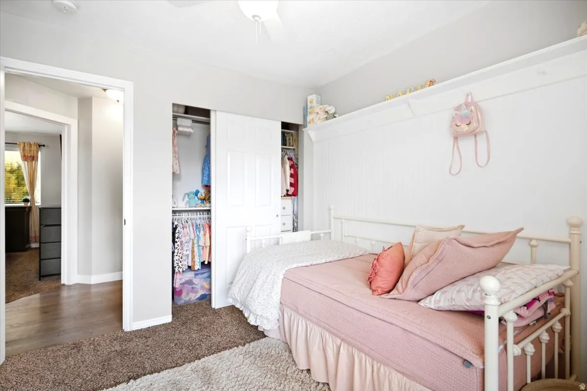Spacious bedroom with sliding closet doors, built-in wall shelving, and warm-toned carpeting
