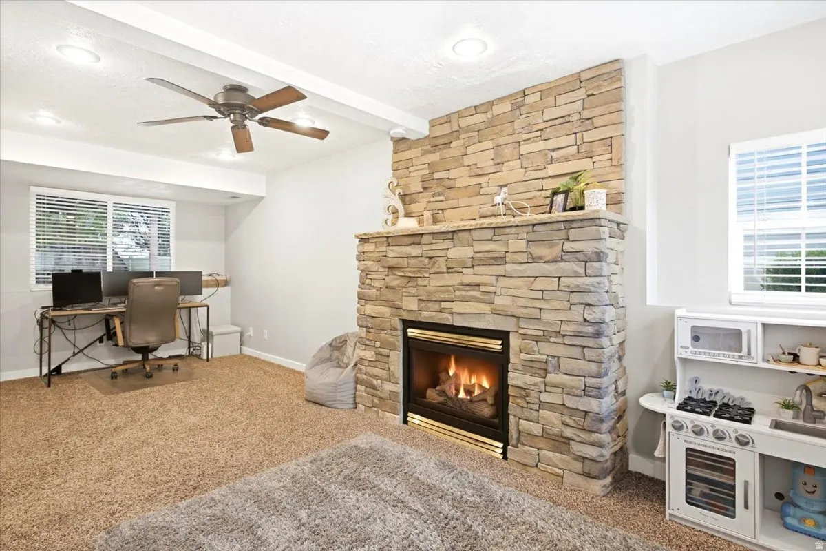 Stone veneer fireplace with mantel, recessed lighting, and ceiling fan