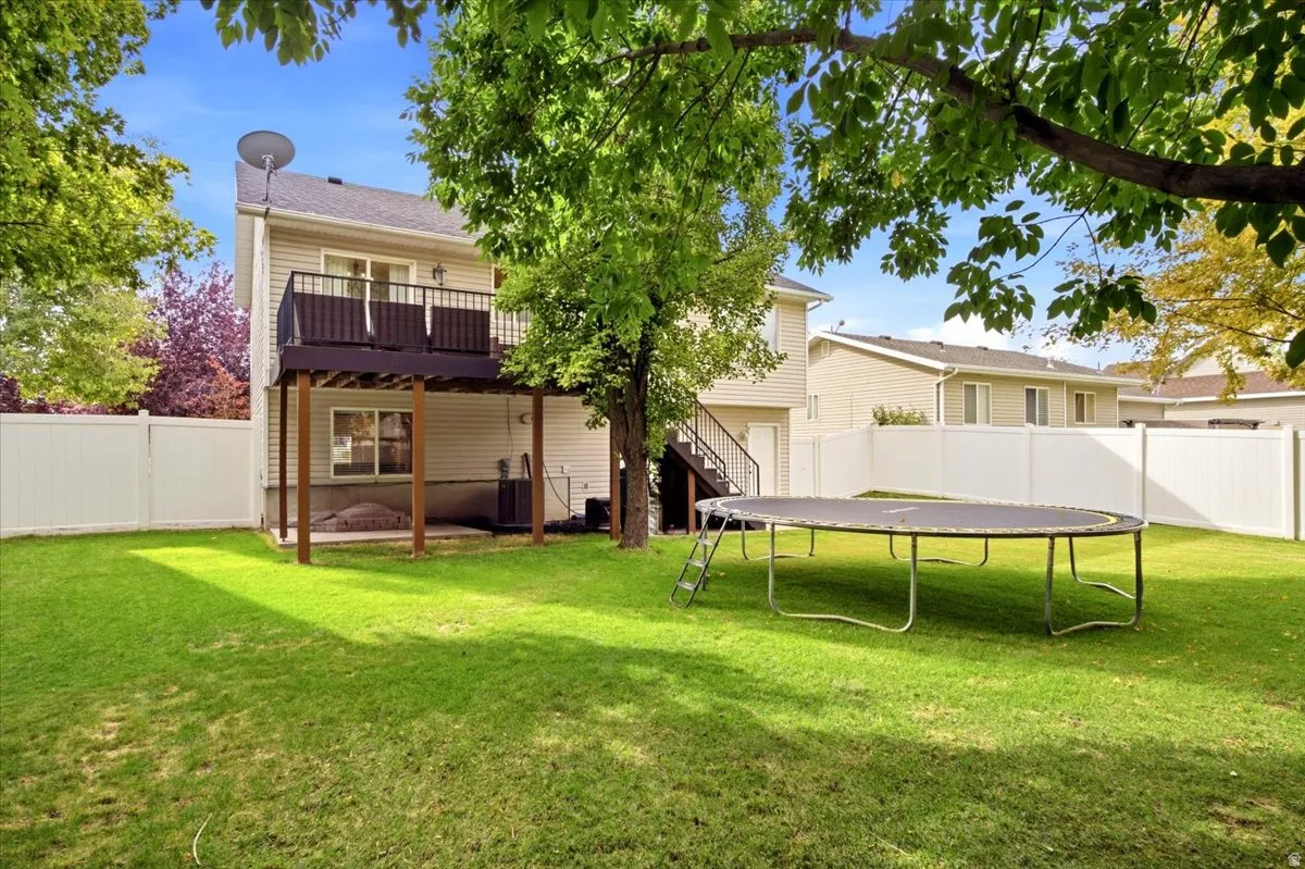 Expansive backyard featuring a manicured lawn, established trees, and a full privacy fence