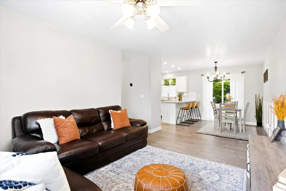 Recessed lighting, wood-finish flooring, white walls, built-in ceiling fan, and a kitchen pass-through