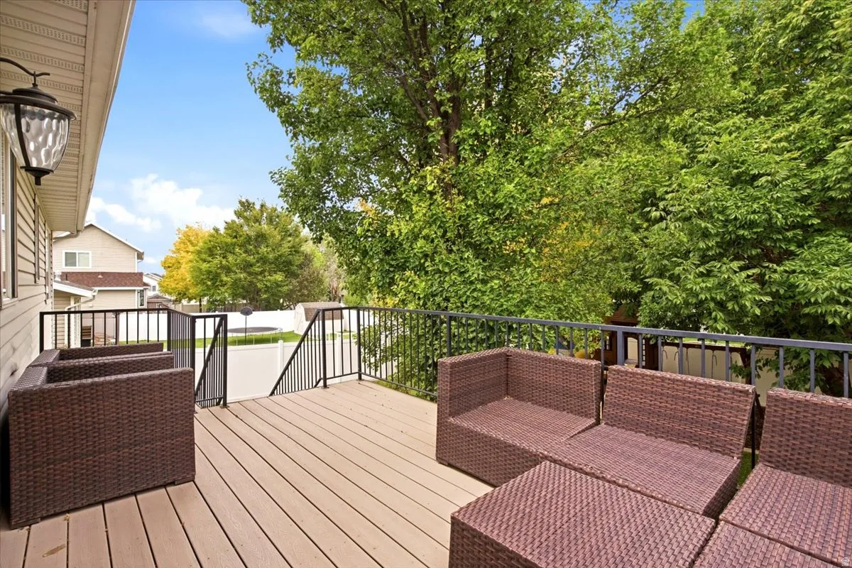 Expansive outdoor deck featuring wood-finish flooring, black metal railings, and an exterior wall lantern