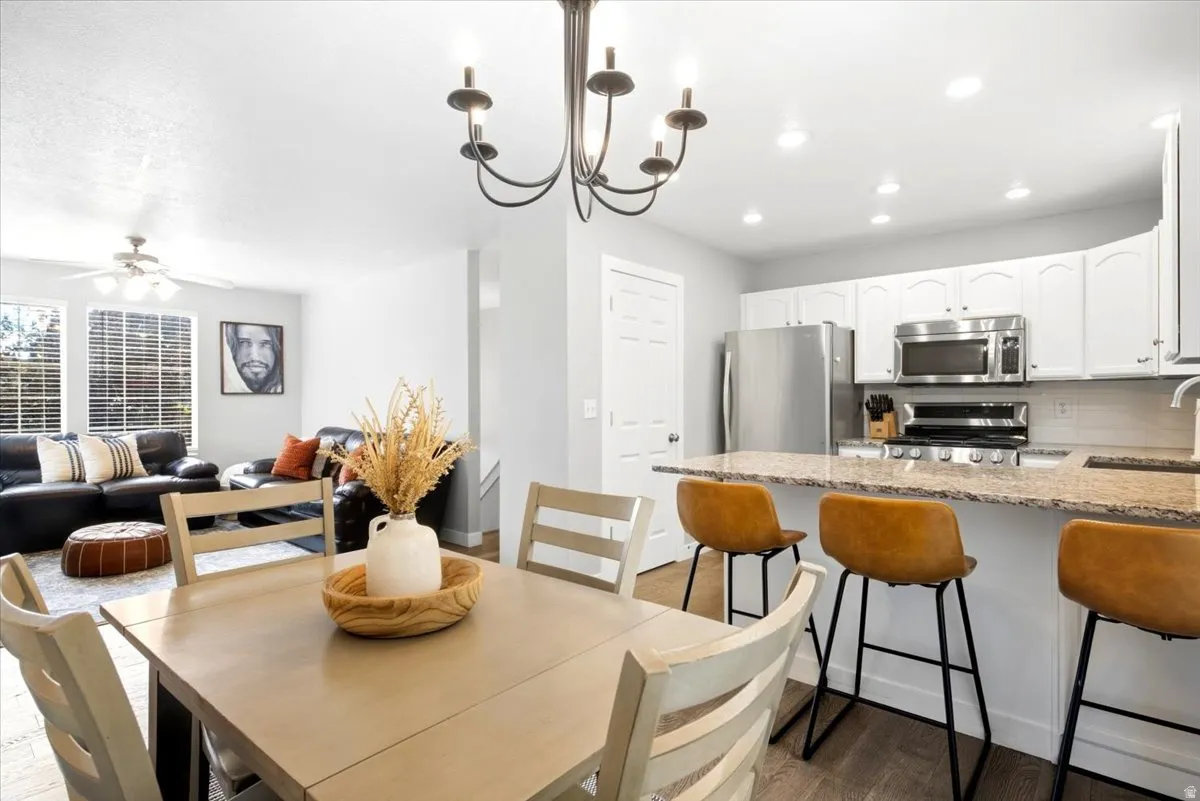Modern kitchen featuring white cabinetry, stainless steel appliances, and a granite-style countertop breakfast bar