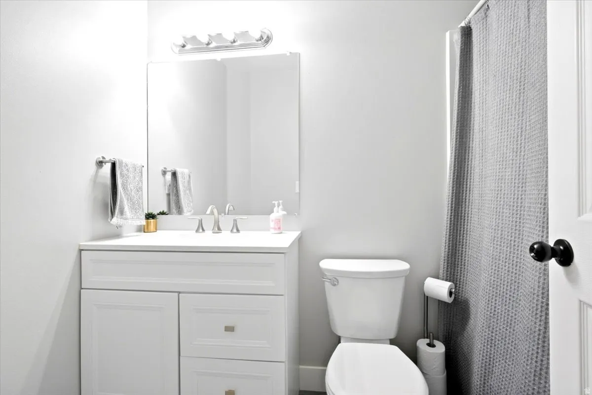 White vanity with recessed panel doors and drawers, a seamless countertop, and a rectangular undermount sink
