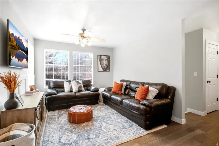 Recessed lighting and ceiling fan fixture illuminate the living area with wood-finish flooring