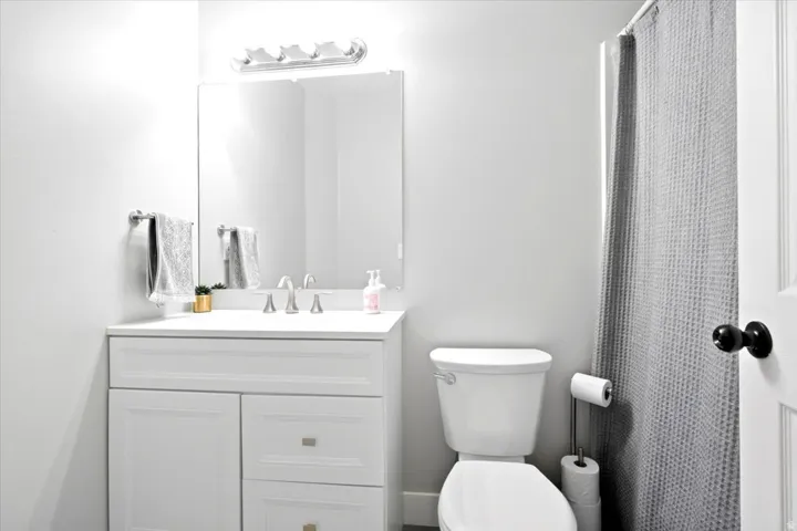 White vanity with recessed panel doors and drawers, a seamless countertop, and a rectangular undermount sink
