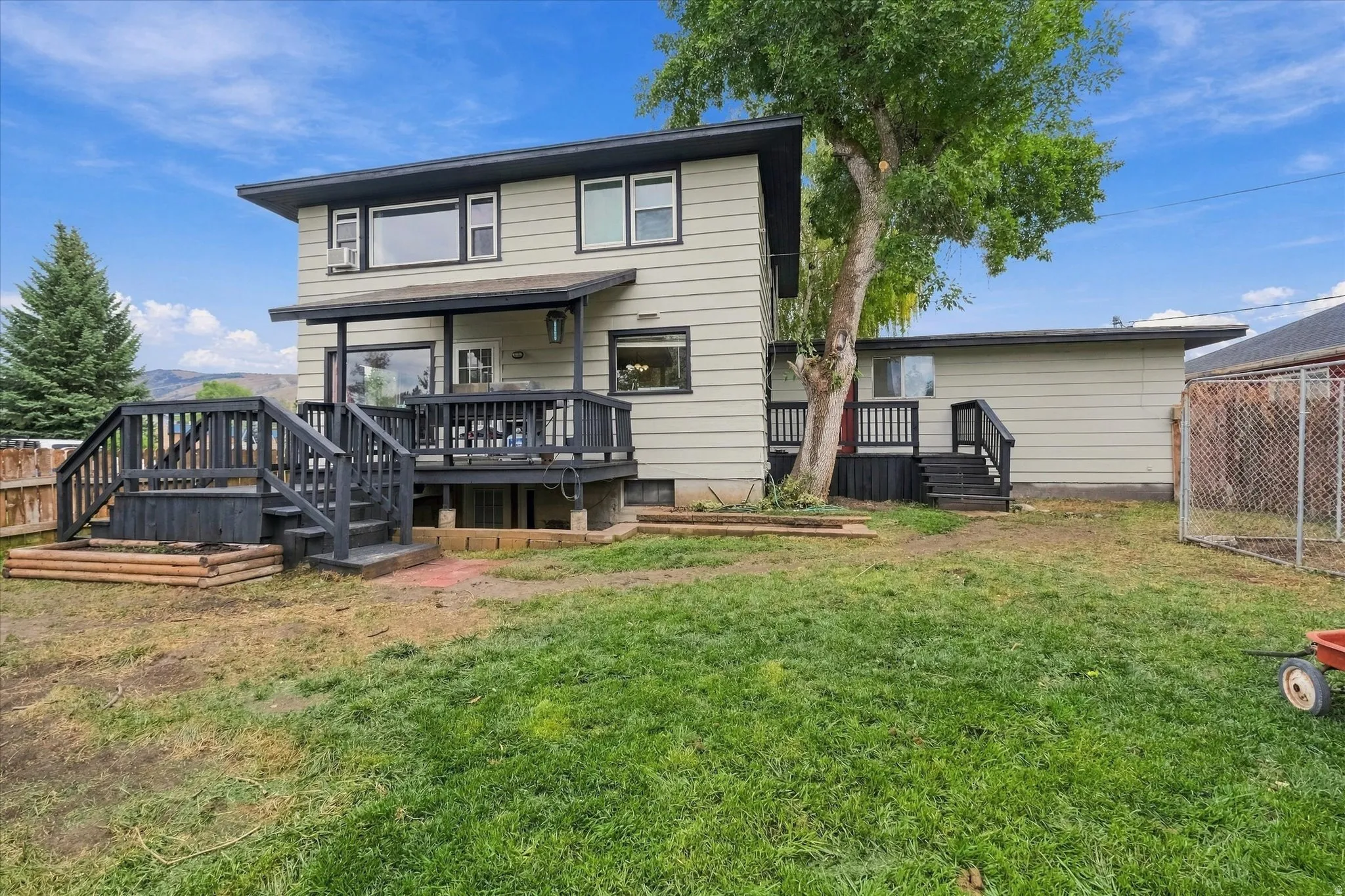 Expansive backyard featuring a multi-level deck, covered patio area, and mature trees