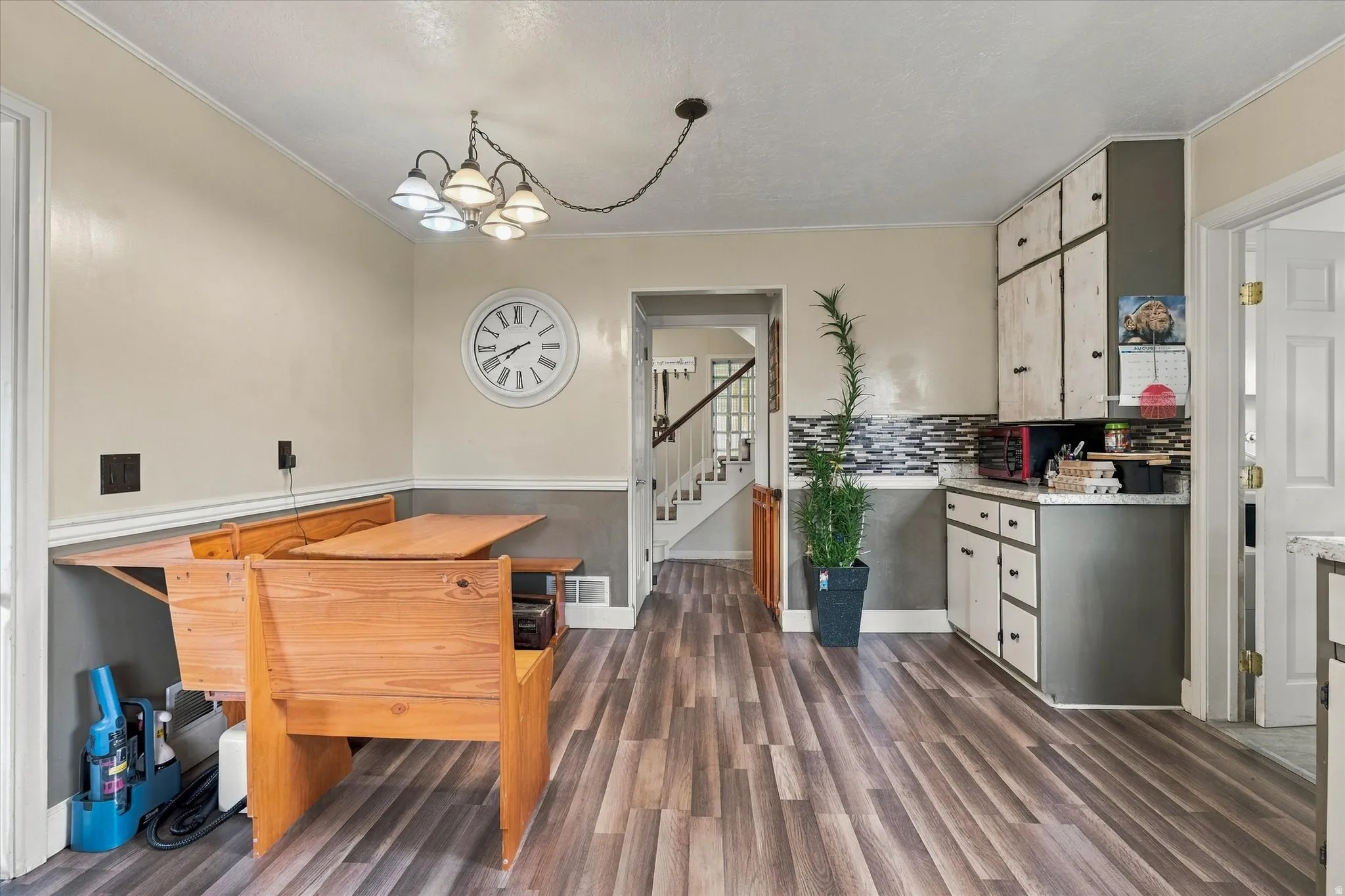 Wood-finish flooring throughout, two-tone wall paint, built-in cabinetry, and a mosaic tile backsplash