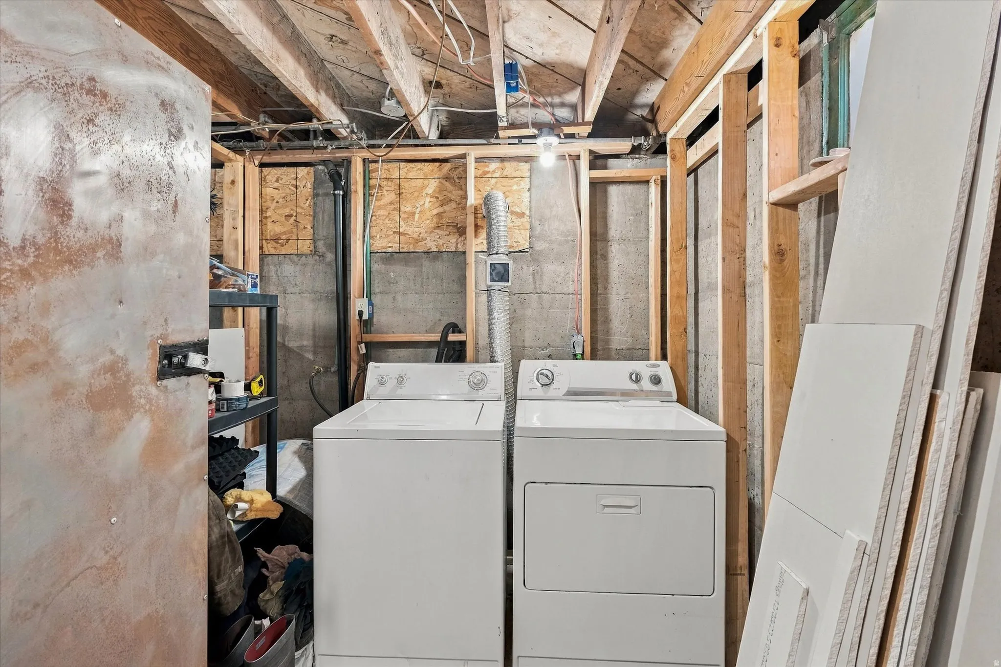 Laundry area featuring a washing machine and dryer, exposed ceiling joists, and framed wall construction