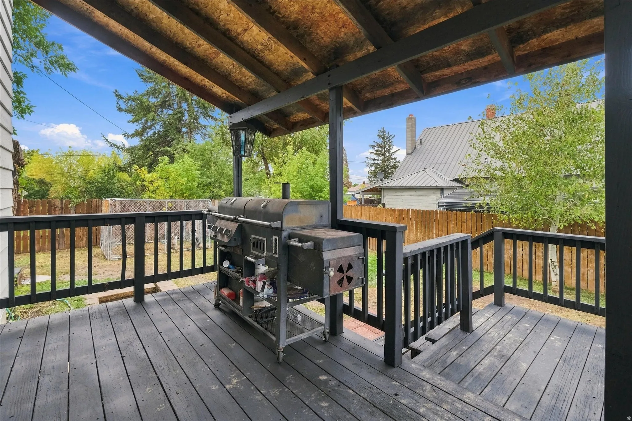 Covered wood-finish deck with black railings and exposed wood ceiling beams