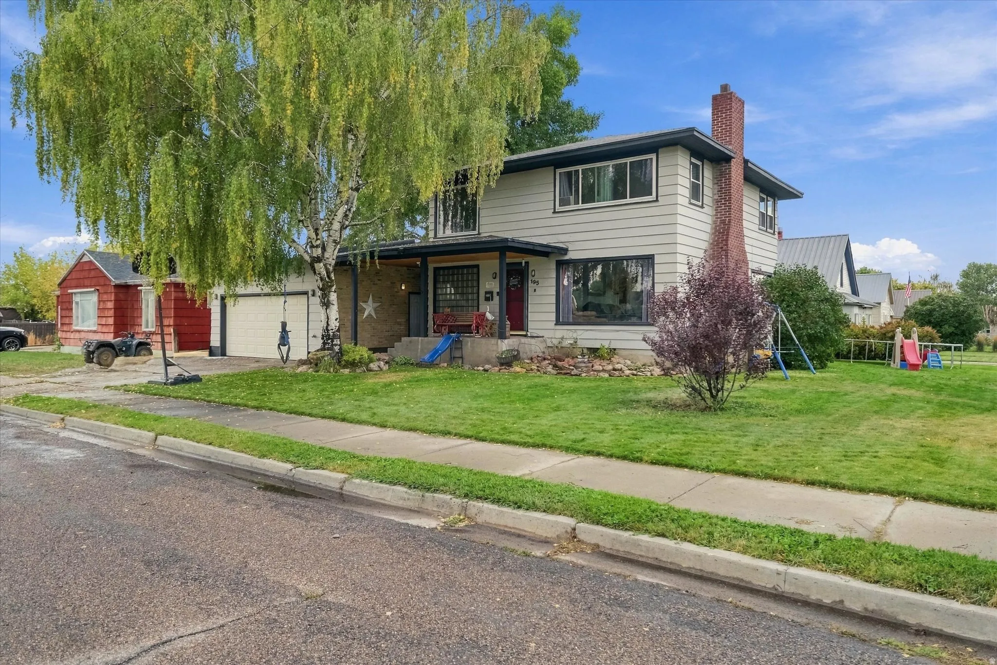 Two-story residence with a brick chimney, an attached two-car garage, and a covered front entry