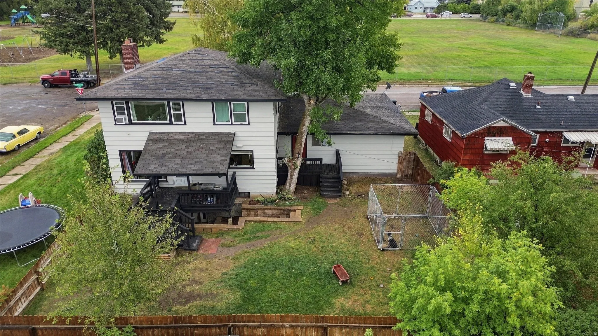 White siding exterior, black trim windows, multi-level decking, attached garage, and a wood privacy fence