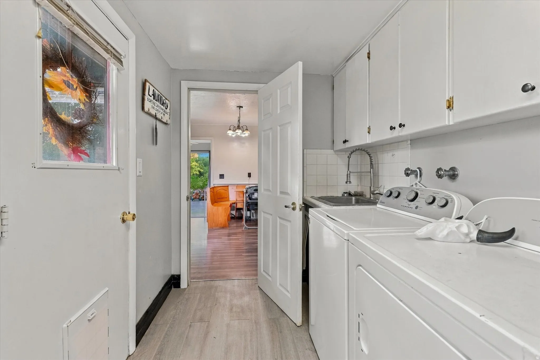 Utility room featuring built-in cabinetry, a utility sink with a gooseneck faucet, and light wood-finish flooring