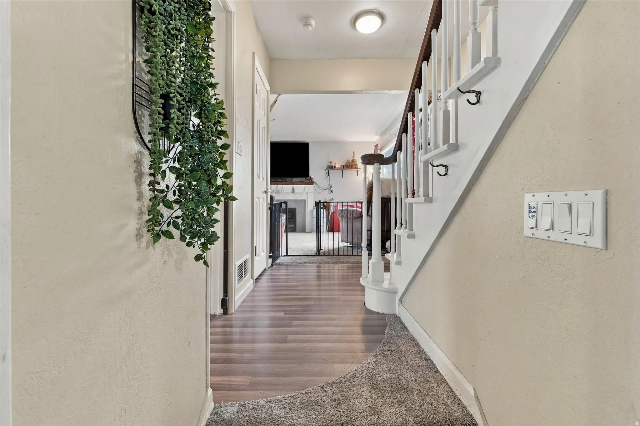 Wood-finish flooring, staircase with white risers and dark wood handrail, recessed lighting, and light-colored wall paint