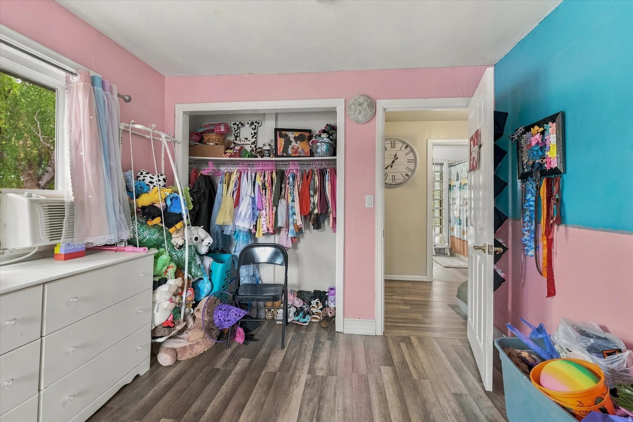 Wood-finish flooring with a window, an open closet, and a white door frame