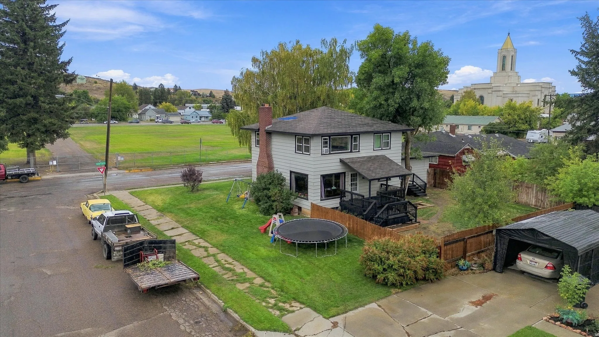 Two-story residence with a covered porch, wood fence, and a detached carport