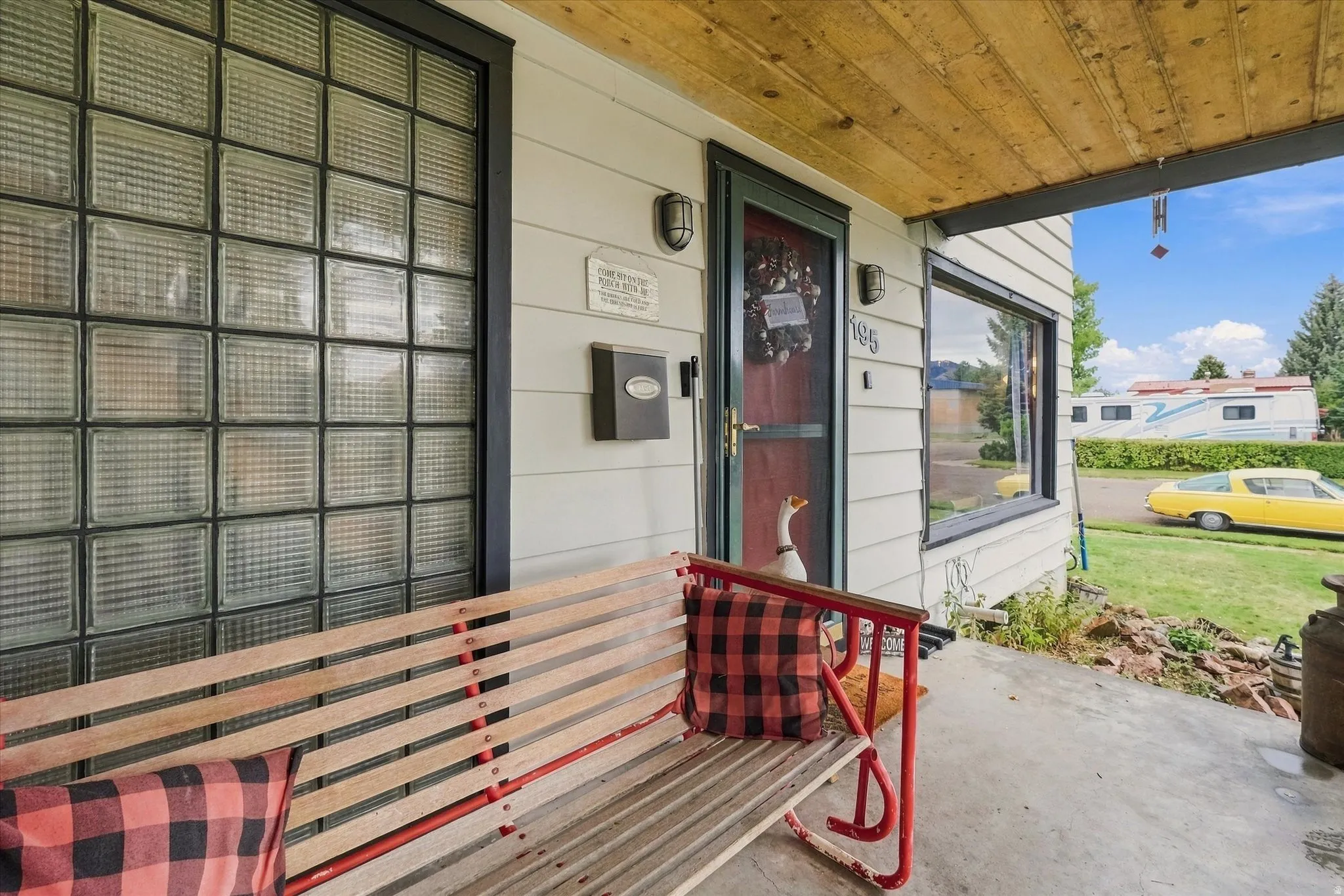 Front porch featuring a concrete surface, wood-slat porch swing, and wood plank ceiling