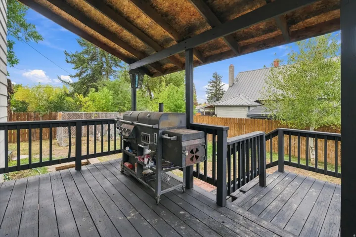 Covered wood-finish deck with black railings and exposed wood ceiling beams