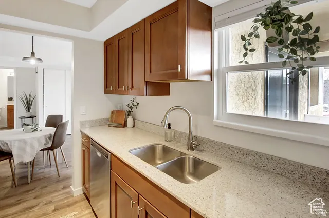 Wood-finish flooring, light-toned countertops, stainless steel dual-basin sink, and a white-framed window