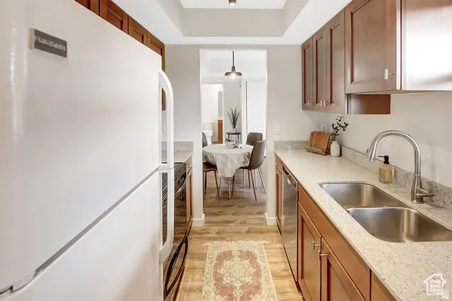 Galley kitchen featuring wood-finish cabinetry, light-toned countertops, and wood-finish flooring