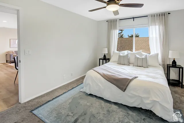 Recessed lighting, wood-finish flooring, ceiling fan, carpeted bedroom, and a window with sheer curtains