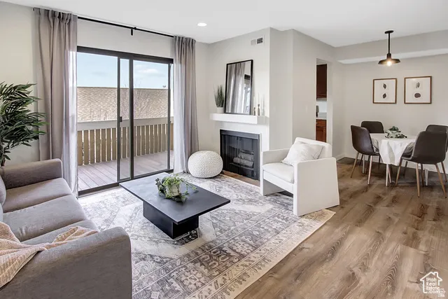 Open concept living space featuring wood-finish flooring, a contemporary fireplace, and sliding glass doors leading to a private balcony