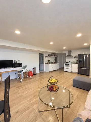 Recessed lighting, wood-finish flooring, white cabinetry, stainless steel appliances, and a built-in range hood