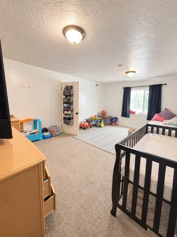 Carpeted flooring, white walls, flush mount lighting, and a window with dark curtains