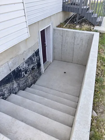 Concrete exterior stairwell leading to a basement entry