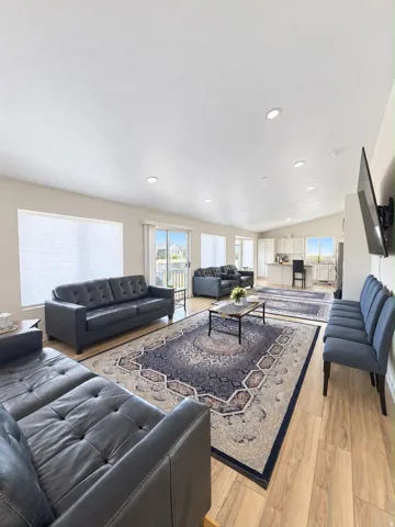 Recessed lighting, wood-finish flooring, white kitchen cabinetry, sliding glass doors, and light-toned walls
