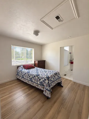 Wood-finish flooring, white walls, and a window with multiple panes