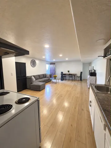 Open-concept living area featuring wood-finish flooring, recessed lighting, and a white electric range with a built-in oven