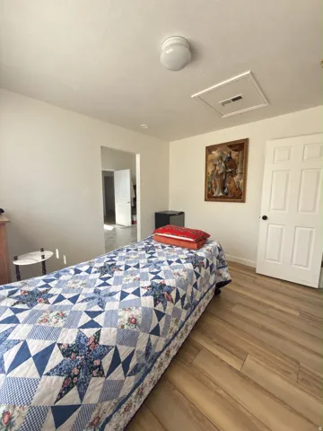 Wood-finish flooring throughout, smooth white walls, and a classic white paneled door