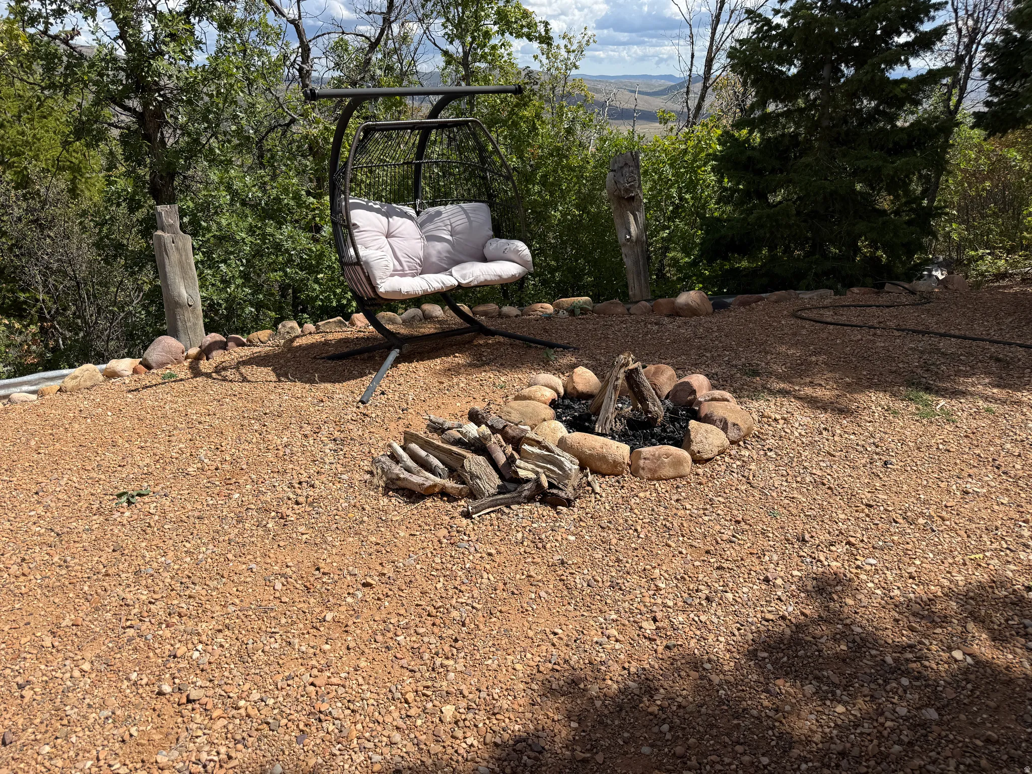 Gravel patio featuring a stone-lined fire pit and a metal swing
