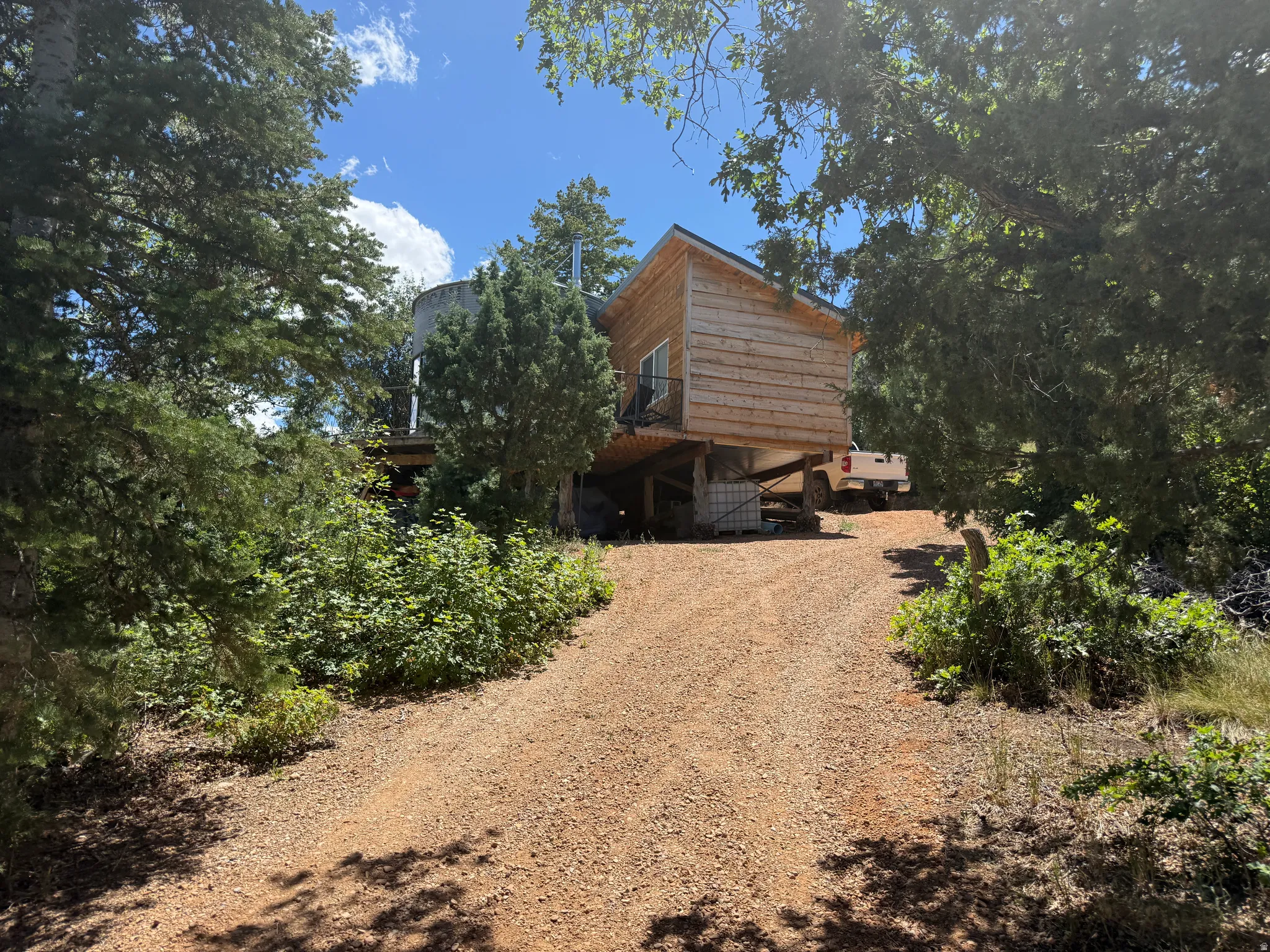 Gravel drive leading to a wood-sided structure with a sloped roof