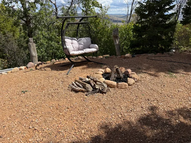 Gravel patio featuring a stone-lined fire pit and a metal swing