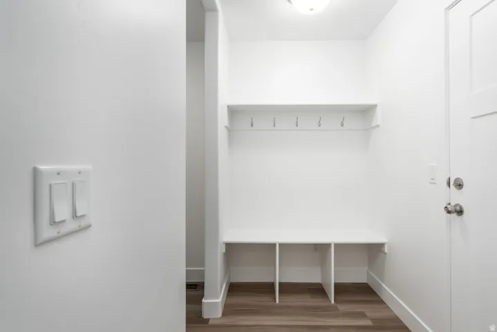Built-in mudroom bench with storage cubbies, wall-mounted coat hooks, and an overhead shelf