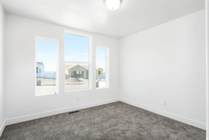 Three large windows, neutral carpet, white walls, and a flush mount ceiling light fixture