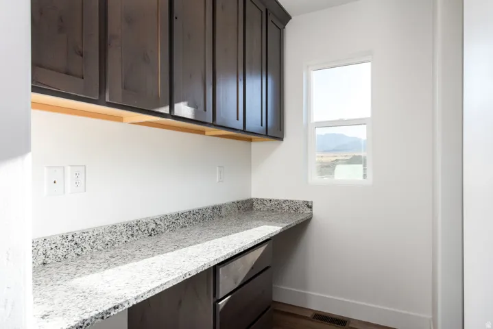 Dark wood-finish cabinetry, light speckled countertops, and wood-finish flooring