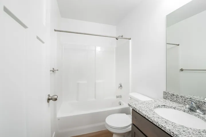 Bathroom featuring a vanity with a light-colored speckled countertop, an undermount sink, and a brushed nickel faucet