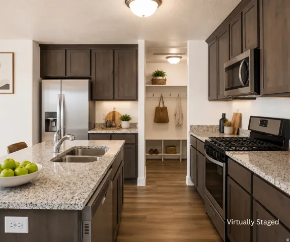 Kitchen featuring wood-finish flooring, dark wood cabinetry, light-toned countertops, and stainless steel appliances