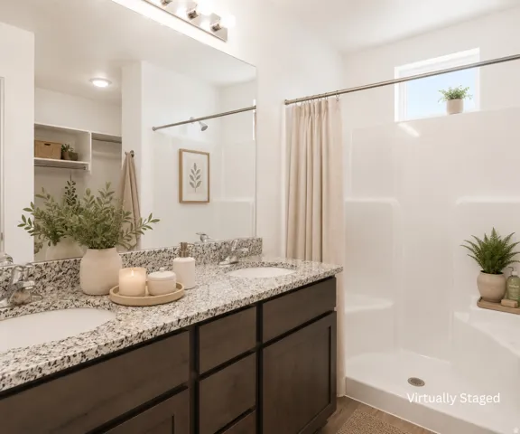 Double vanity with granite countertops, wood-finish cabinetry, and undermount sinks