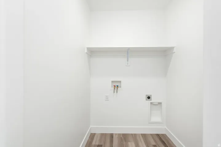 Dedicated utility space featuring a built-in shelf, wood-finish flooring, and crisp white walls