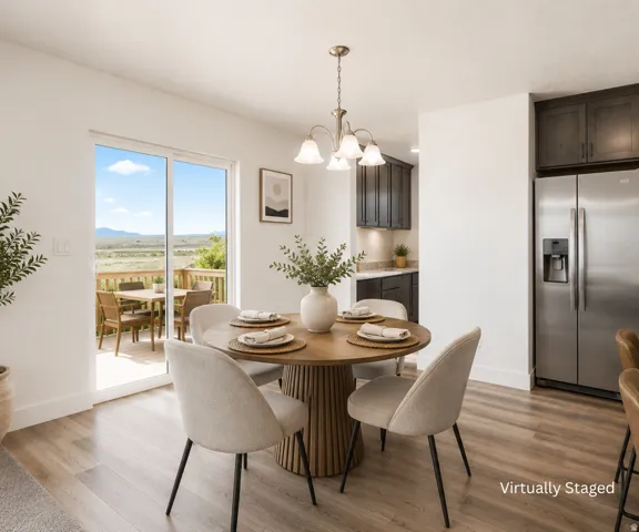 Wood-finish flooring, sliding glass door to exterior deck, stainless steel refrigerator, dark wood-finish cabinetry, and overhead chandelier