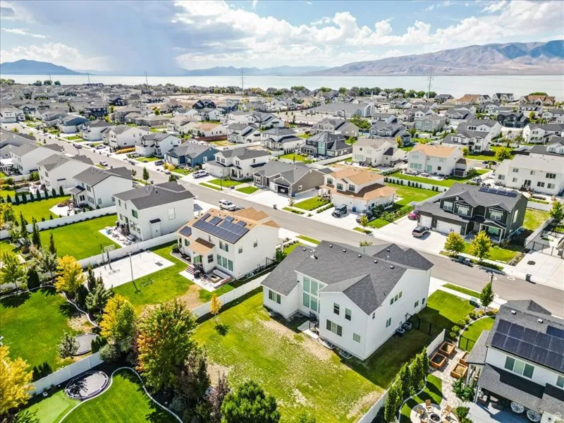 Residential neighborhood with waterside and mountain backdrop, featuring a mix of architectural styles, individual front yards, and paved roadways
