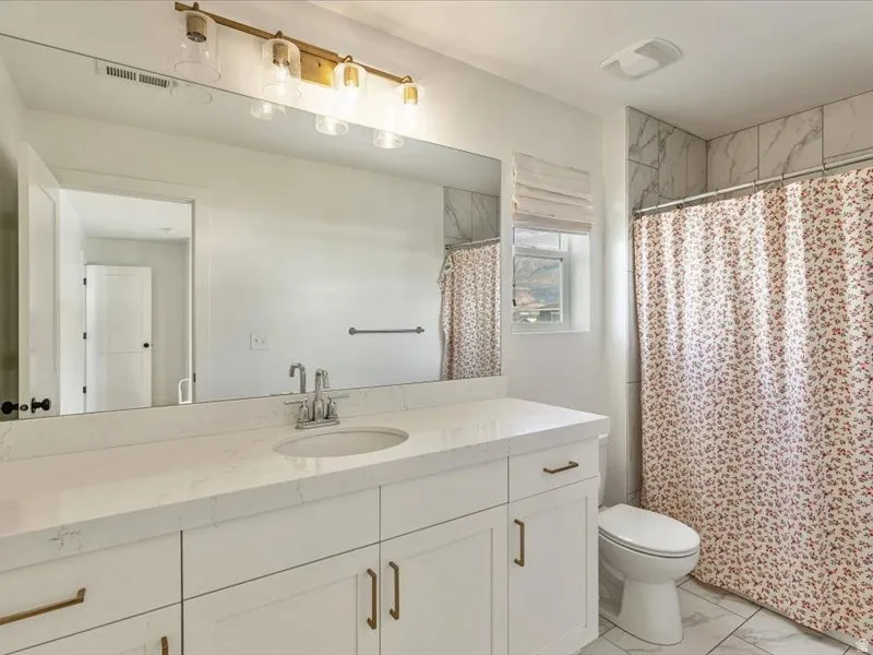 White vanity with integrated sink, brushed nickel faucet, large wall mirror, and modern overhead lighting