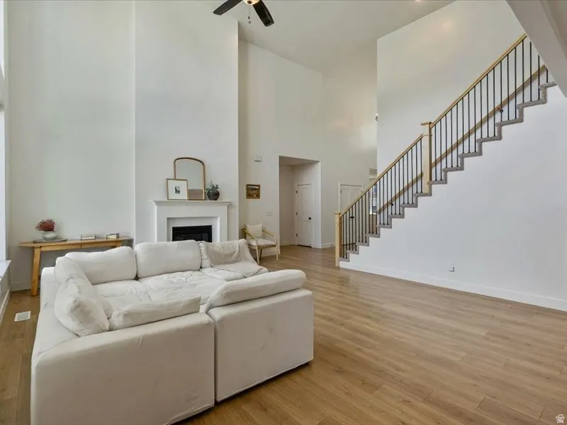 Vaulted ceilings, wood-finish flooring, staircase with metal balusters, and a fireplace with a white mantel